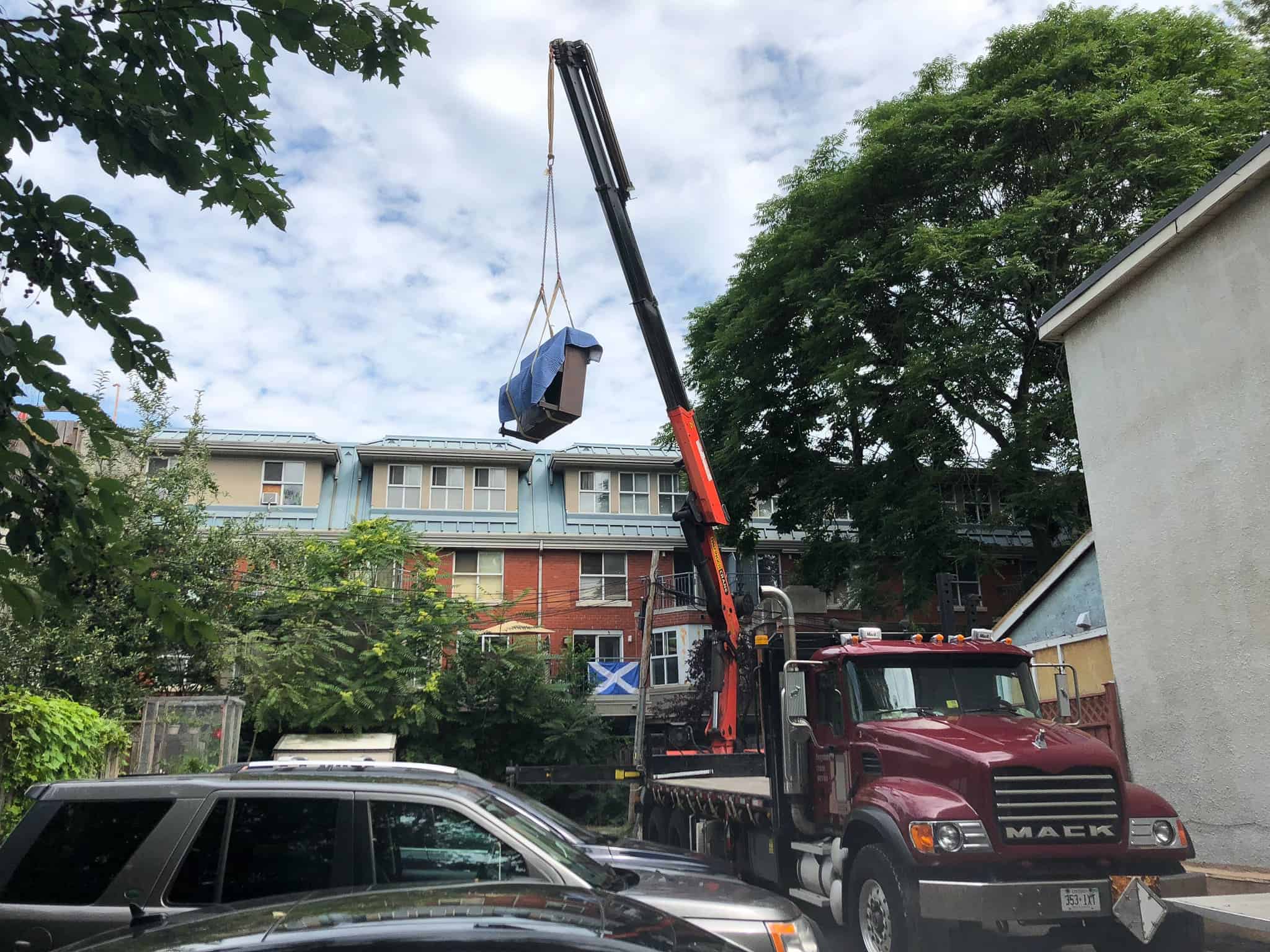 Craning an upright piano onto a backyard balcony in a townhouse complex
