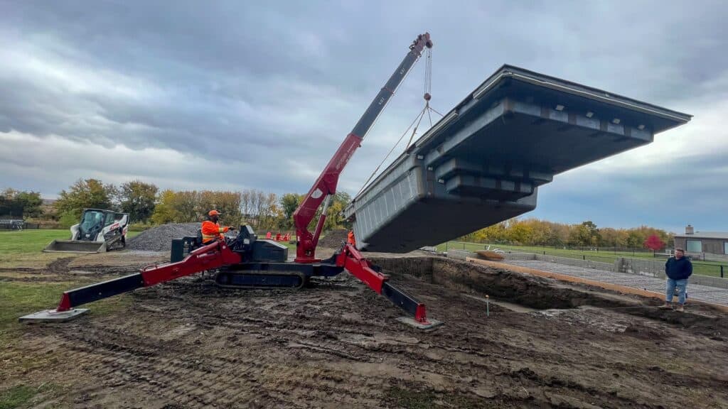 Using a spider crane to lift a swimming pool in a backyard.