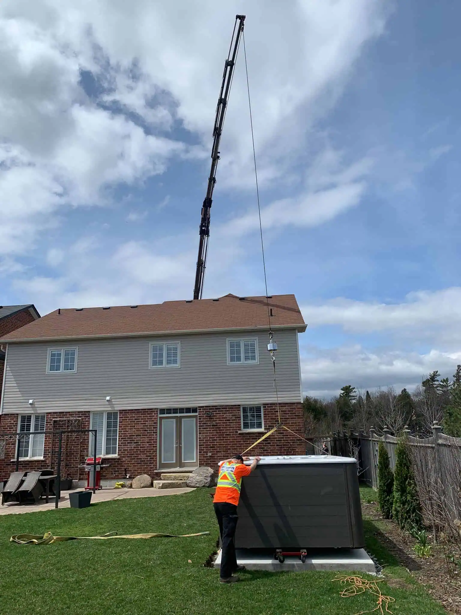 Using crane to position swim spa on a concrete pad in the backyard.