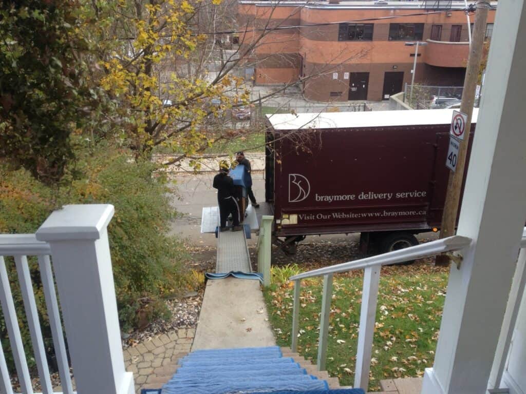 Taking an upright piano up a couple flights of stairs outside a home in Toronto