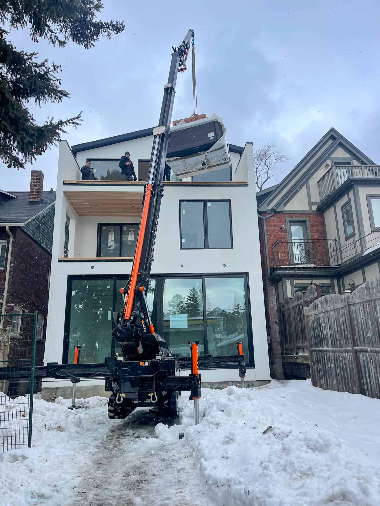 Using a mini crane in backyard to lift a hot tub onto a third floor balcony.
