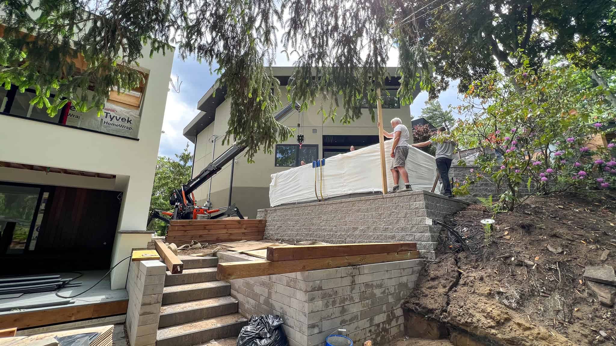 Spider crane lifting swim spa into a difficult backyard placement. Physically impossible to crane from street.