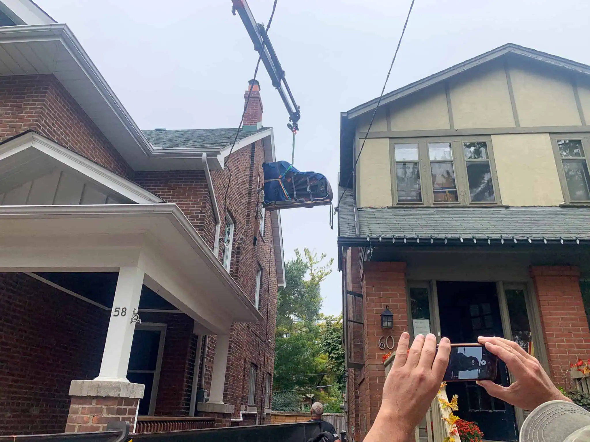 Craning a grand piano in through a window on the third floor of a house.