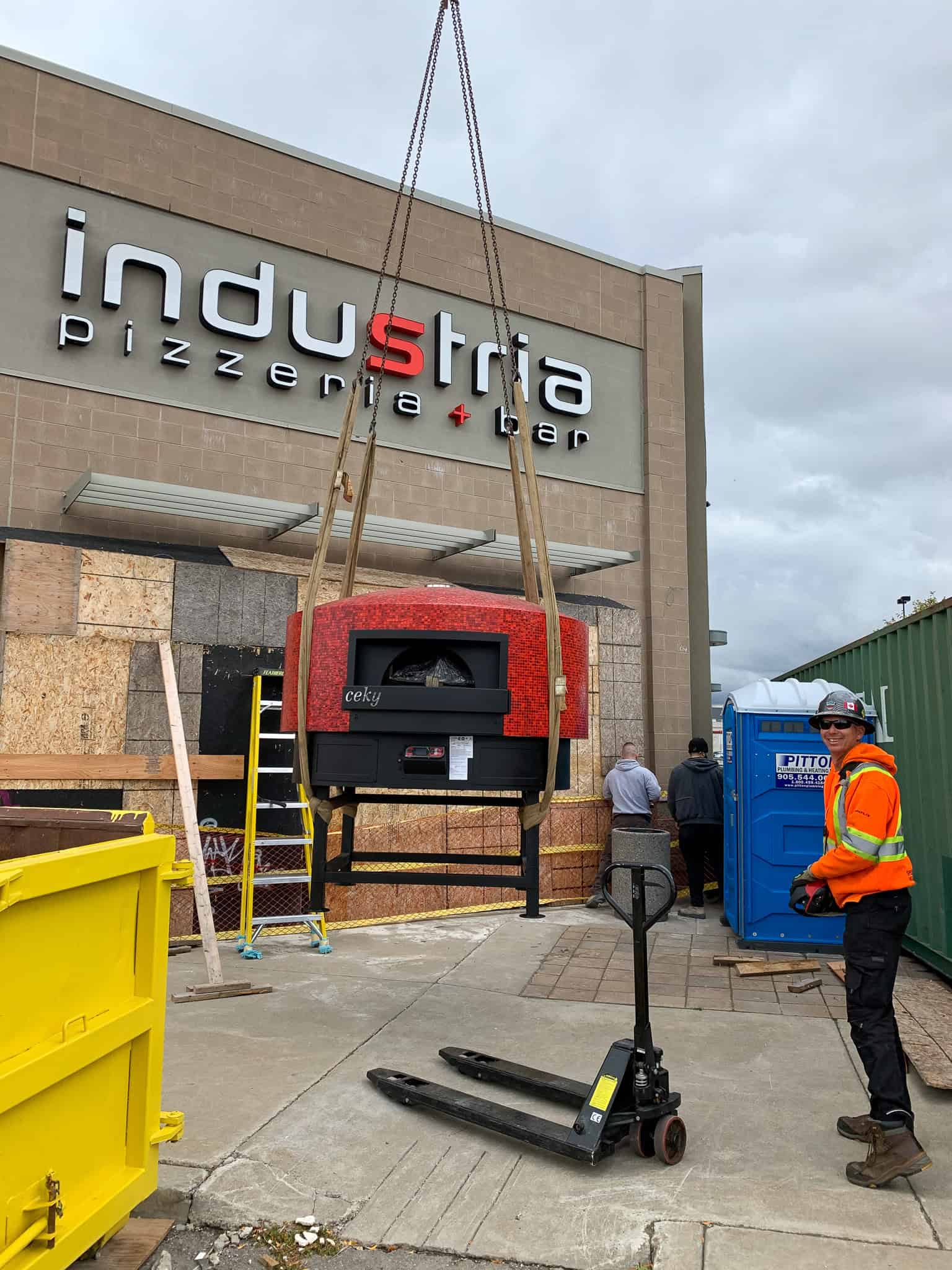 Using crane to lift heavy pizza oven off truck and on to ground in Hamilton.