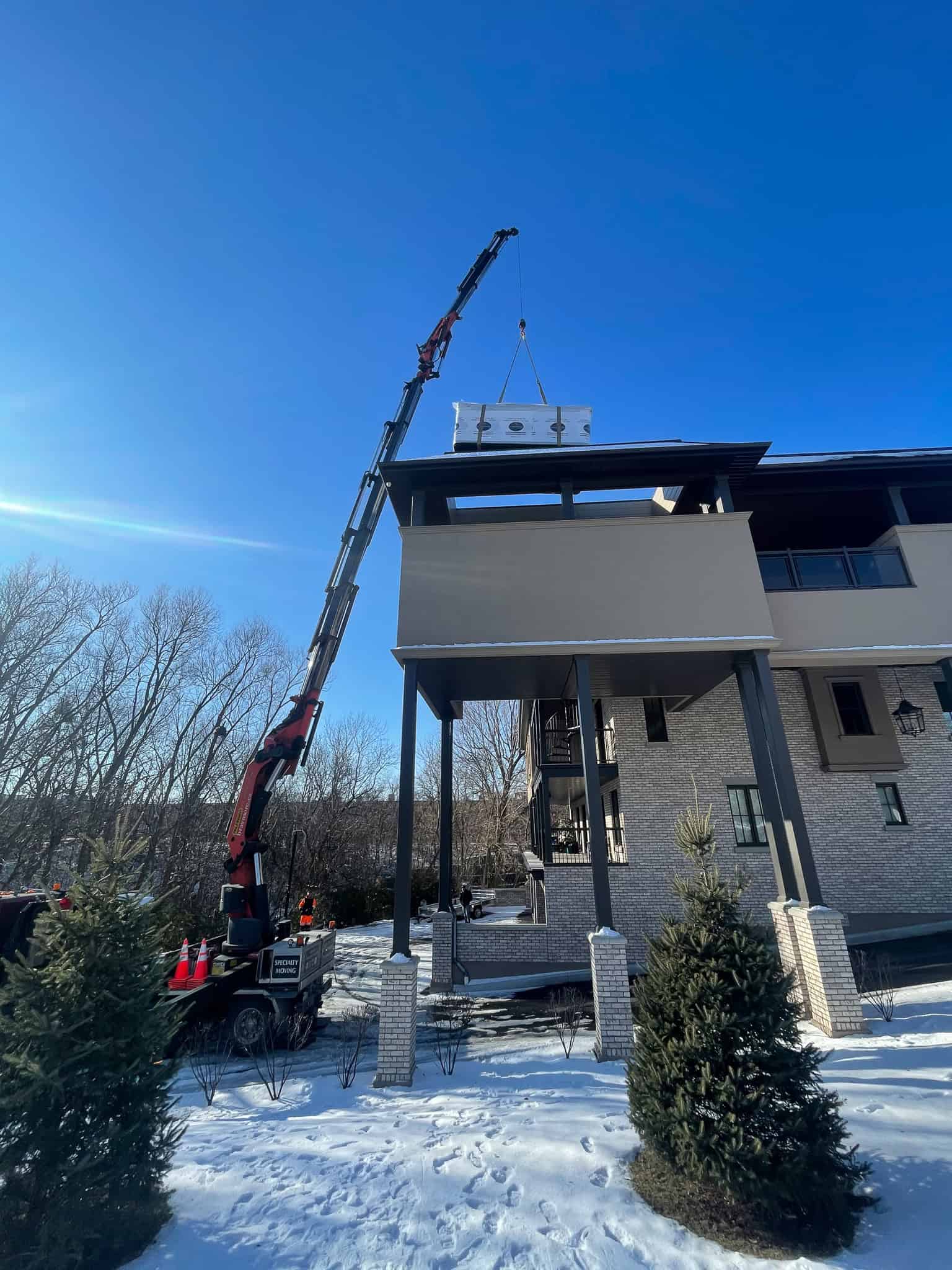PK92002 Knuckle crane lifting a swim spa up onto a raised enclosed balcony.