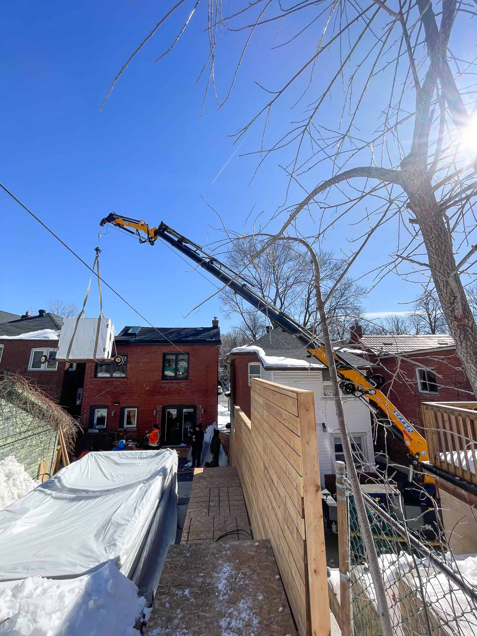Using a spider crane to lift hot tub over a fence from one neighbours yard to another.
