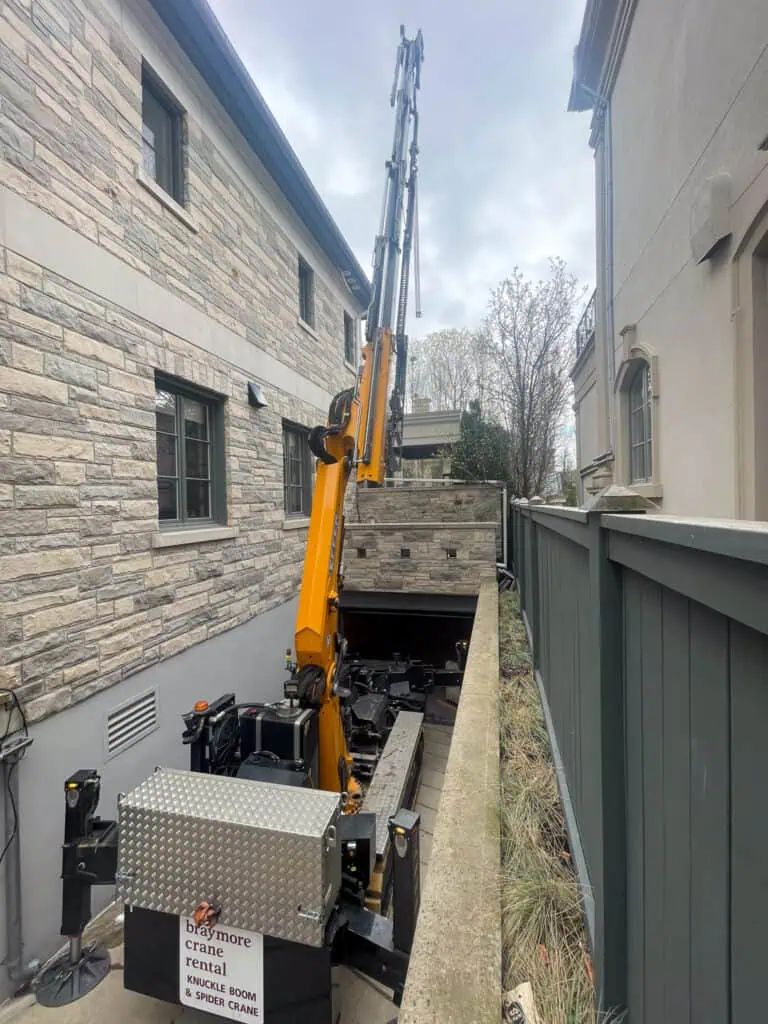 Spider crane lifting a 1900 pound backup generator into a backyard.