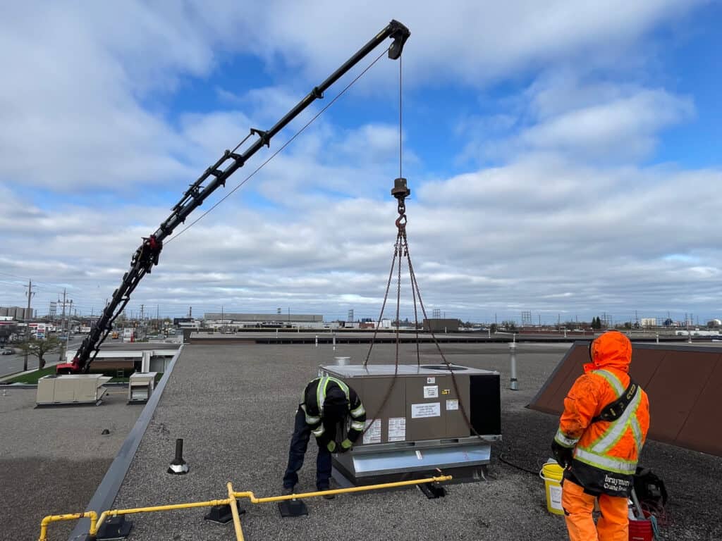 Crane HVAC unit onto a rooftop in a restricted zone.  See how low the crane boom is.