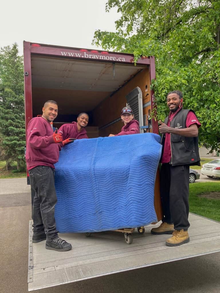 Piano movers using a truck tailgate to lift upright piano into their piano moving truck.