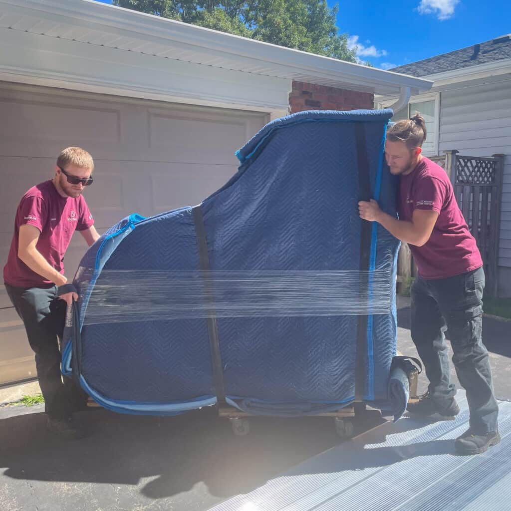 Rolling grand piano off tailgate of truck and into a customers home.