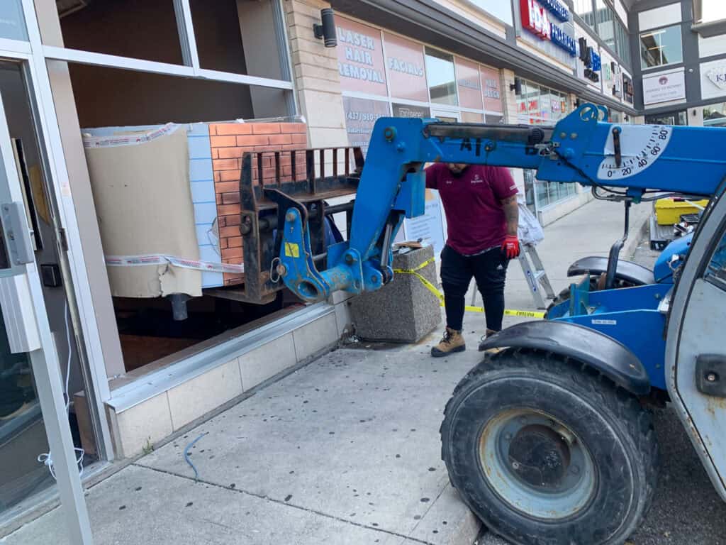 Using a tele-handler to lift a 3000 pound pizza oven in thru a window of a pizzeria.