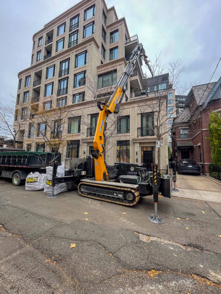 Using a mini crane to lift items up onto a balcony in downtown Toronto.  Using a mini crane on this job site allowed our customer to save money by not closing he street and having to get permits to do so.