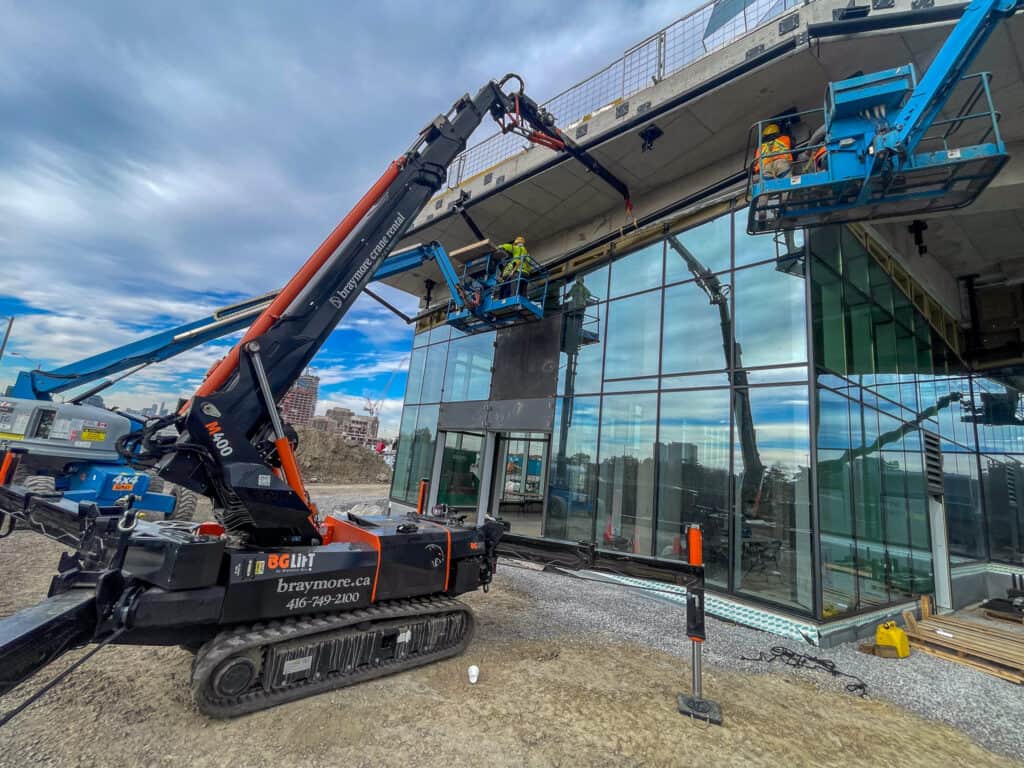 BG Lift mini crane, lifting pipes and materials into place under a balcony.