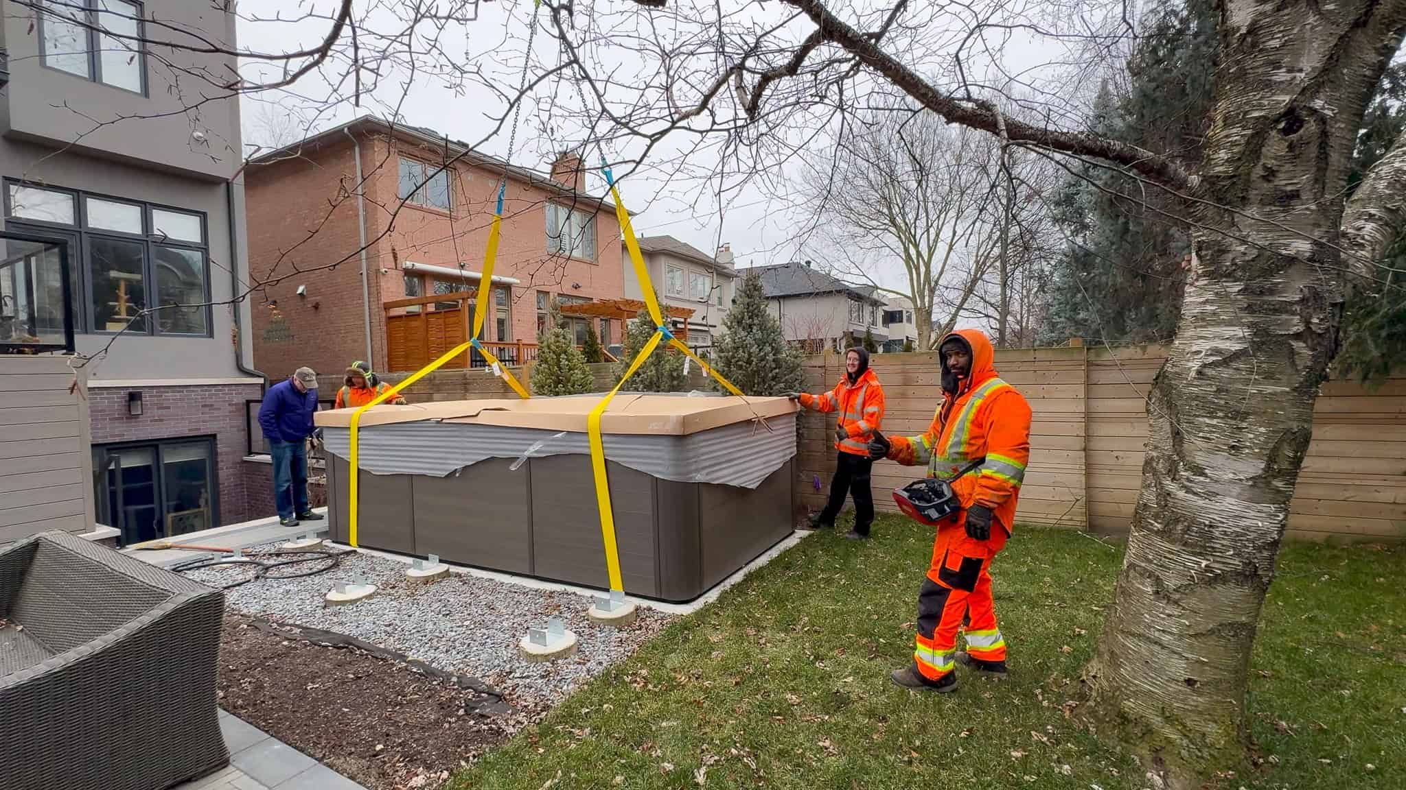 Palfinger PK200002 landing a swim spa on a concrete pad in a backyard.