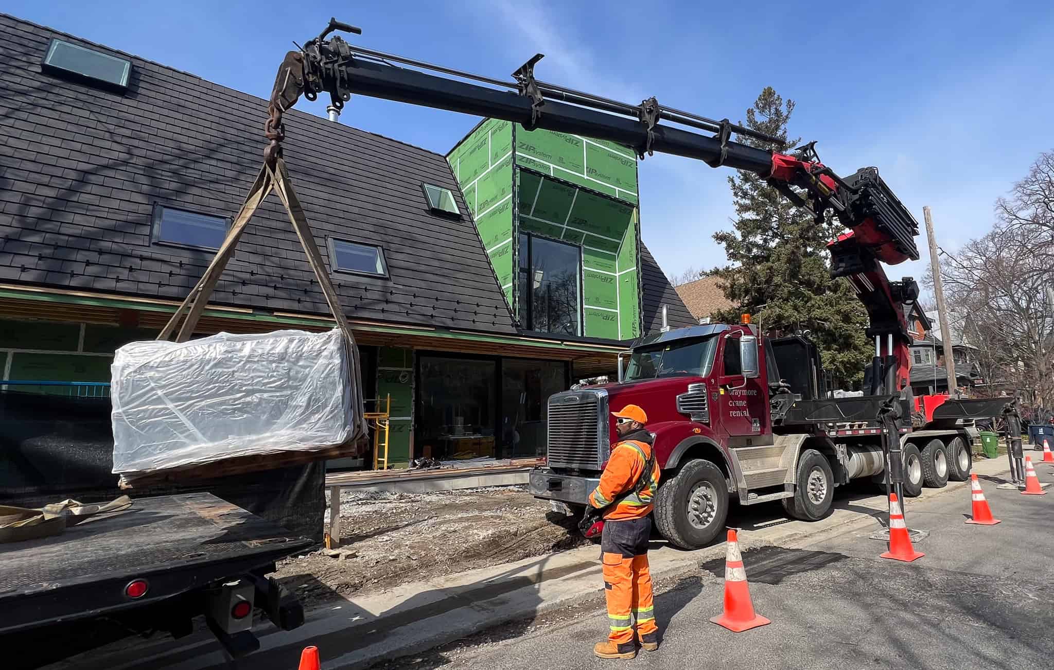 Palfinger 135002 lifting large heavy skids onto a construction site.