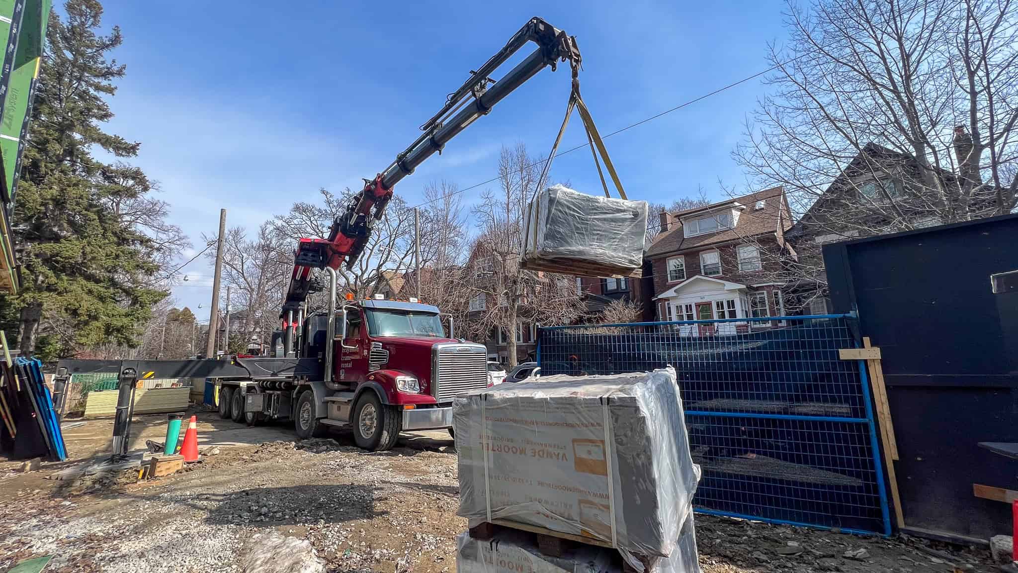 Palfinger 135002 lifting large heavy skids onto a construction site.