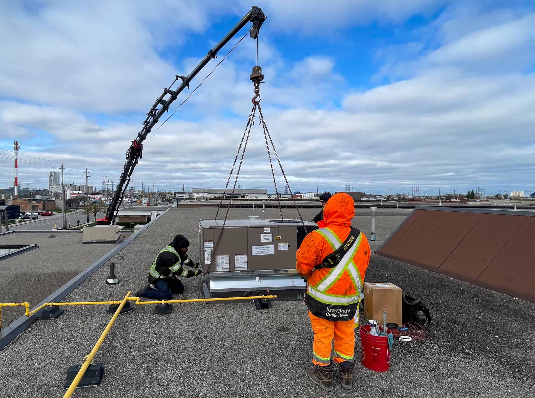 Palfinger 135002 craning HVAC unit into place on rooftop.