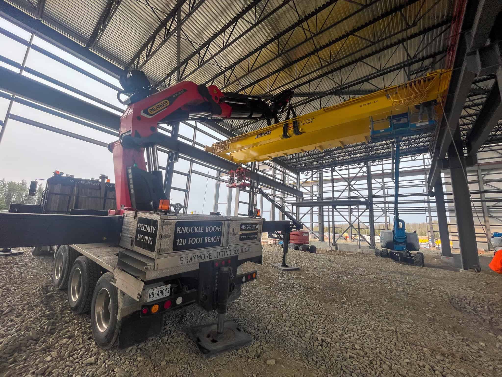 Palfinger 135002 lifting large crane into place inside commercial building.