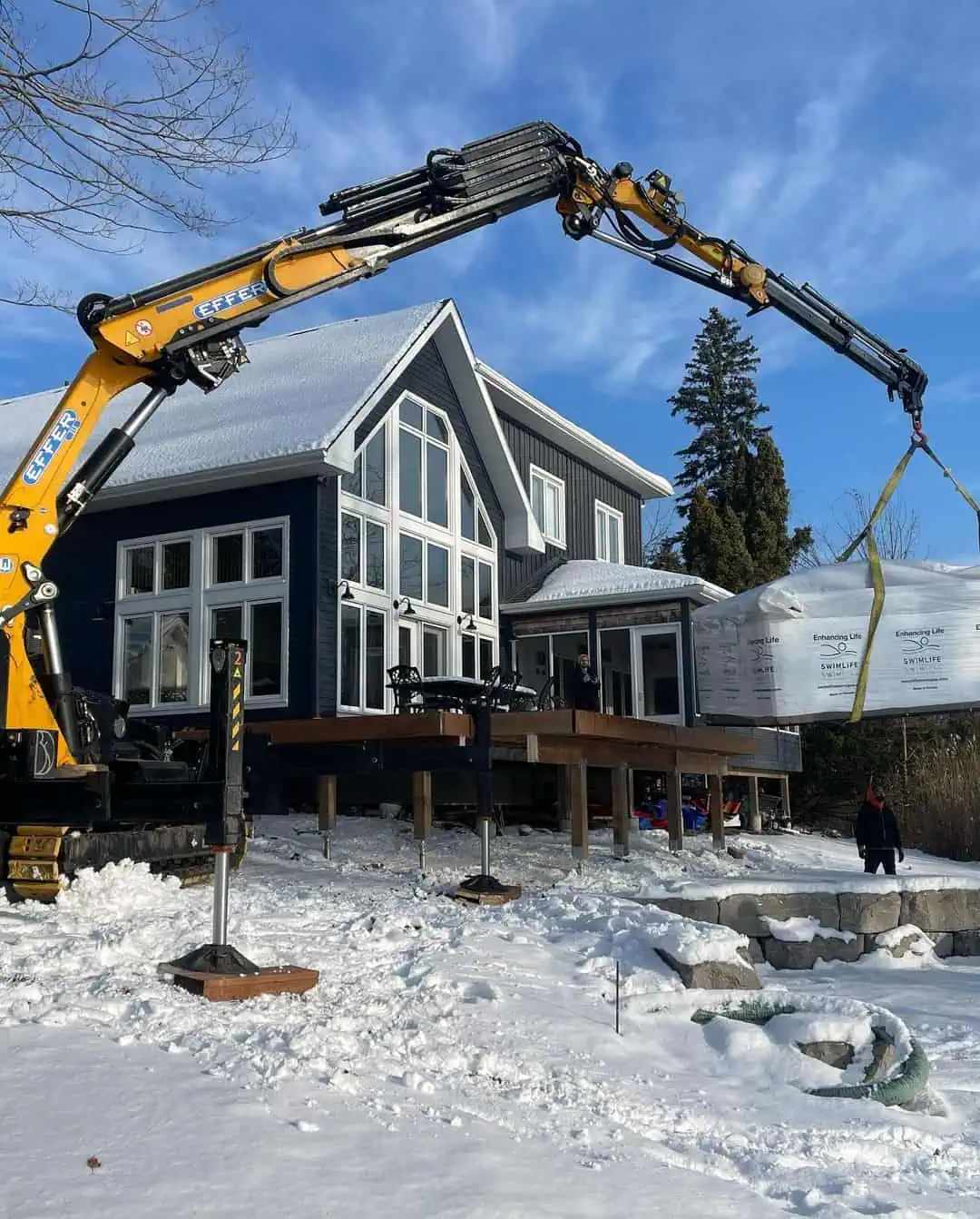 BG Lift CWE315 crane swim spa over snow and uneven ground.