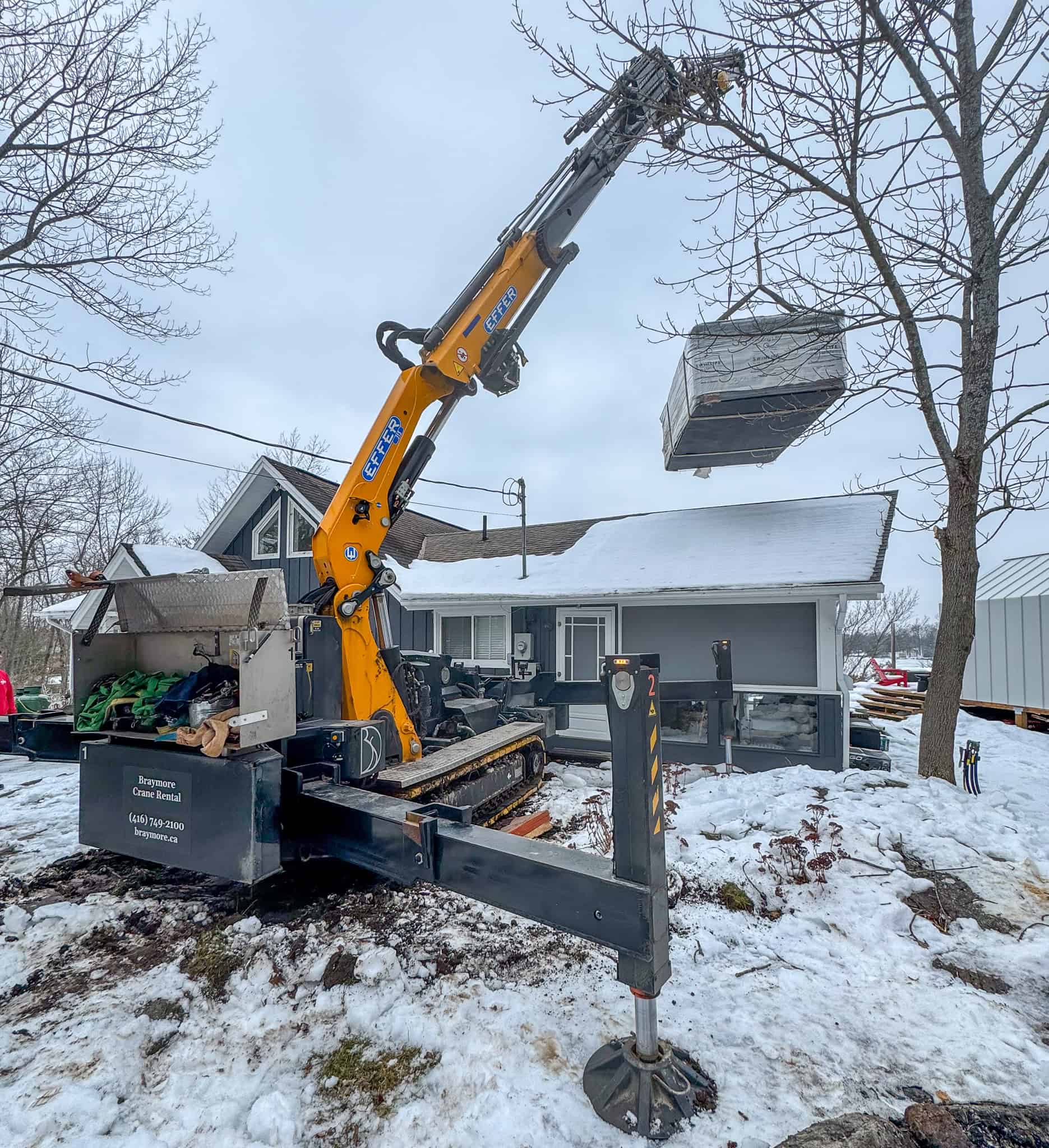 Mini crane lifting a swim spa over a bungalow in Coldwater.