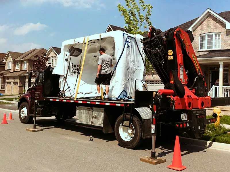 A hot tub being prepared for craning on the back of a knuckle crane.
