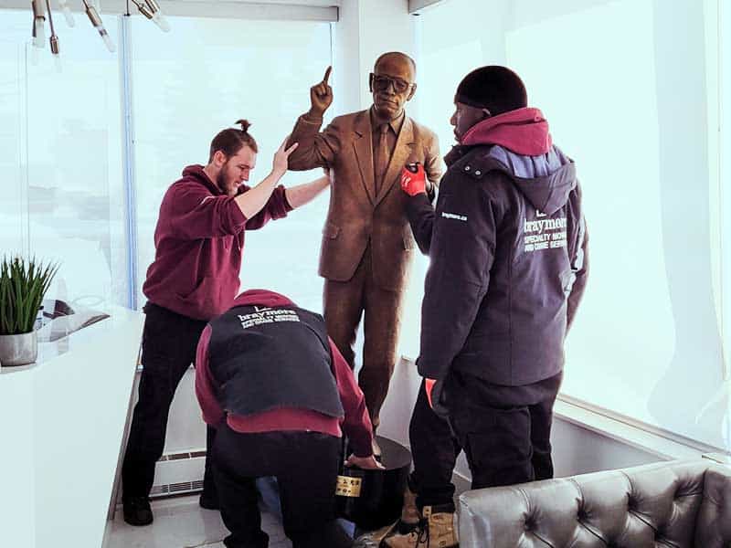 Employees moving a full sized human statue to a new location.