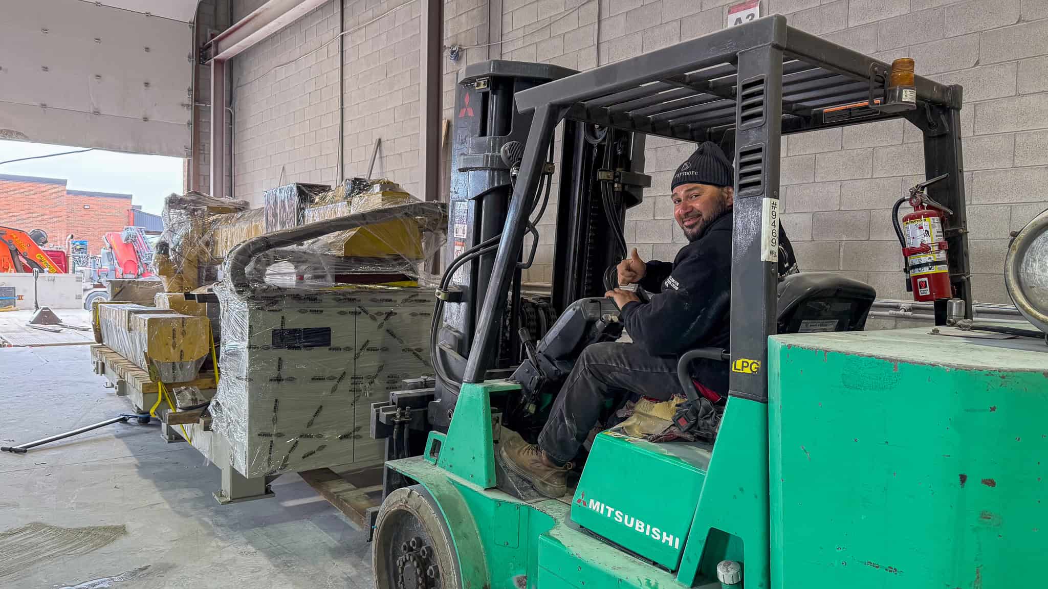 We are using a large forklift to move a large stone cutting table into a workshop.