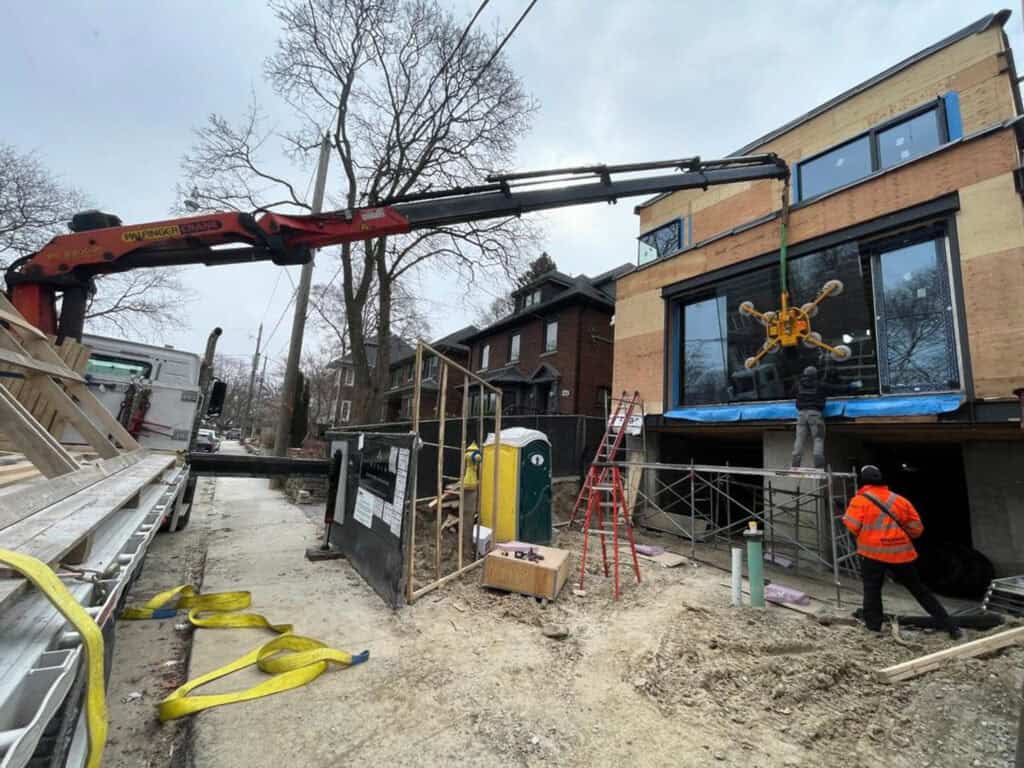 Palfinger PK23002 Knuckle Crane transporting glass windows and lifting them into place.