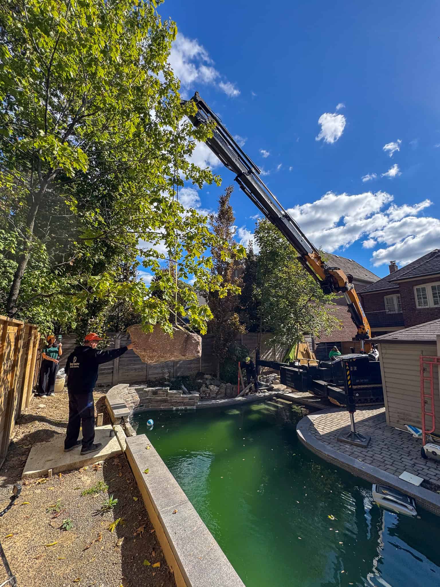 CWE315 Mini Crane lifting a large heavy rock over a pool.