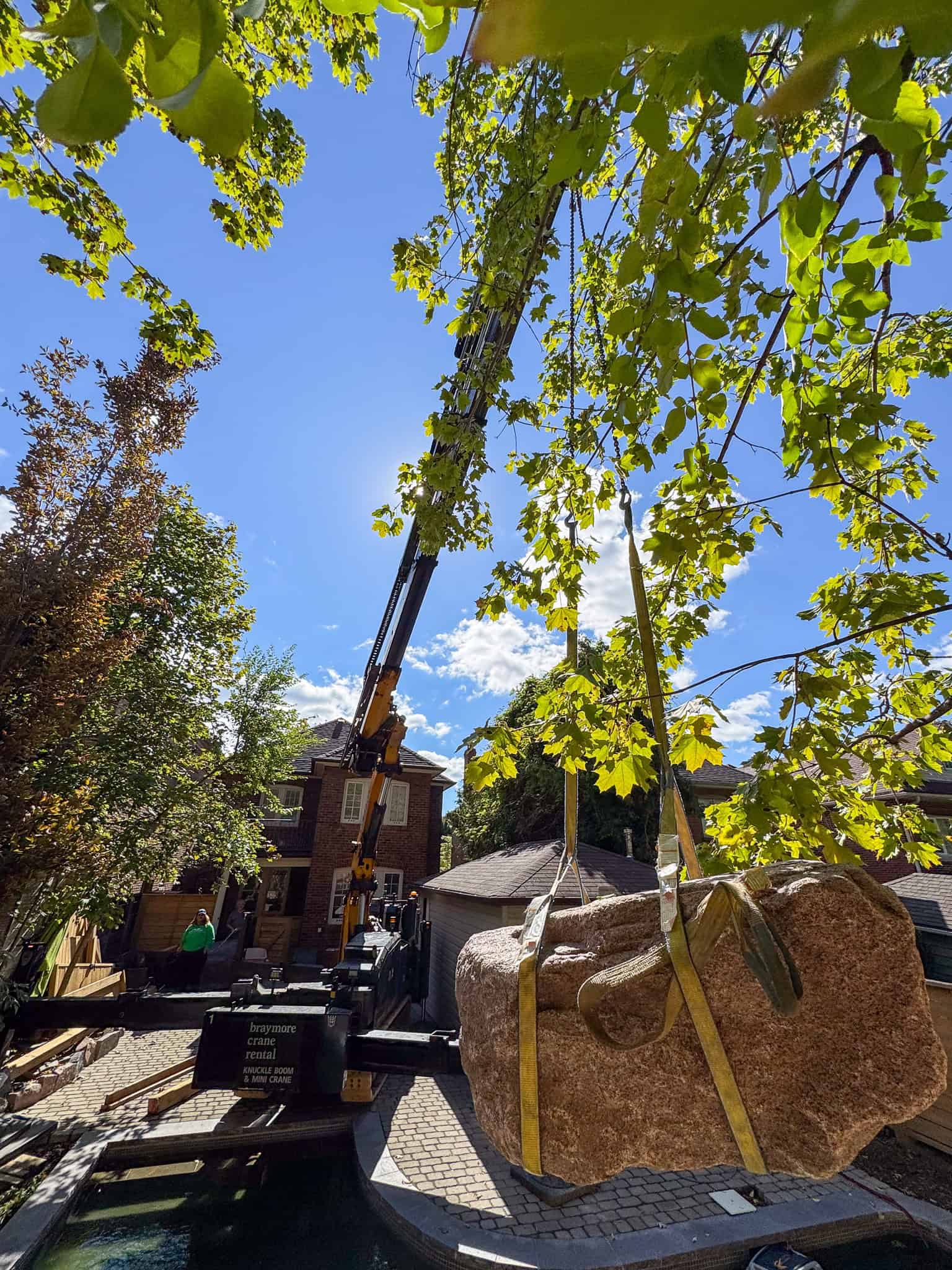 CWE315 Mini Crane lifting a large heavy rock over a pool.